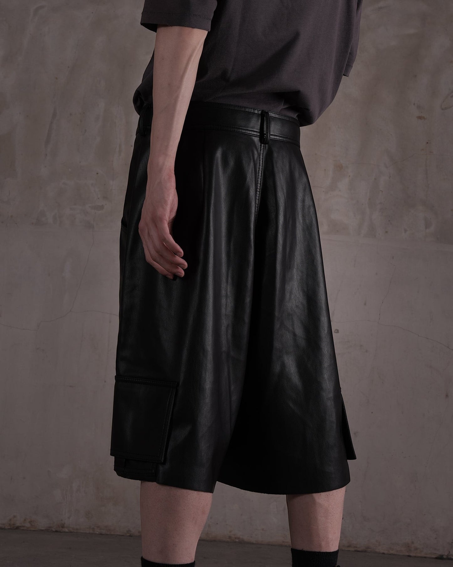 KYOHEY_FUJITAの黒いレザー製ハーフパンツ。デコンストラクトなデザインとサイドポケットが特徴のメンズショートパンツ。