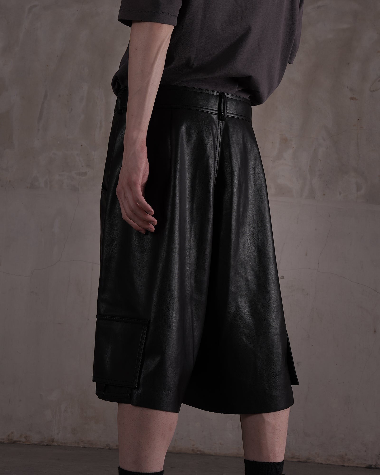 KYOHEY_FUJITAの黒いレザー製ハーフパンツ。デコンストラクトなデザインとサイドポケットが特徴のメンズショートパンツ。