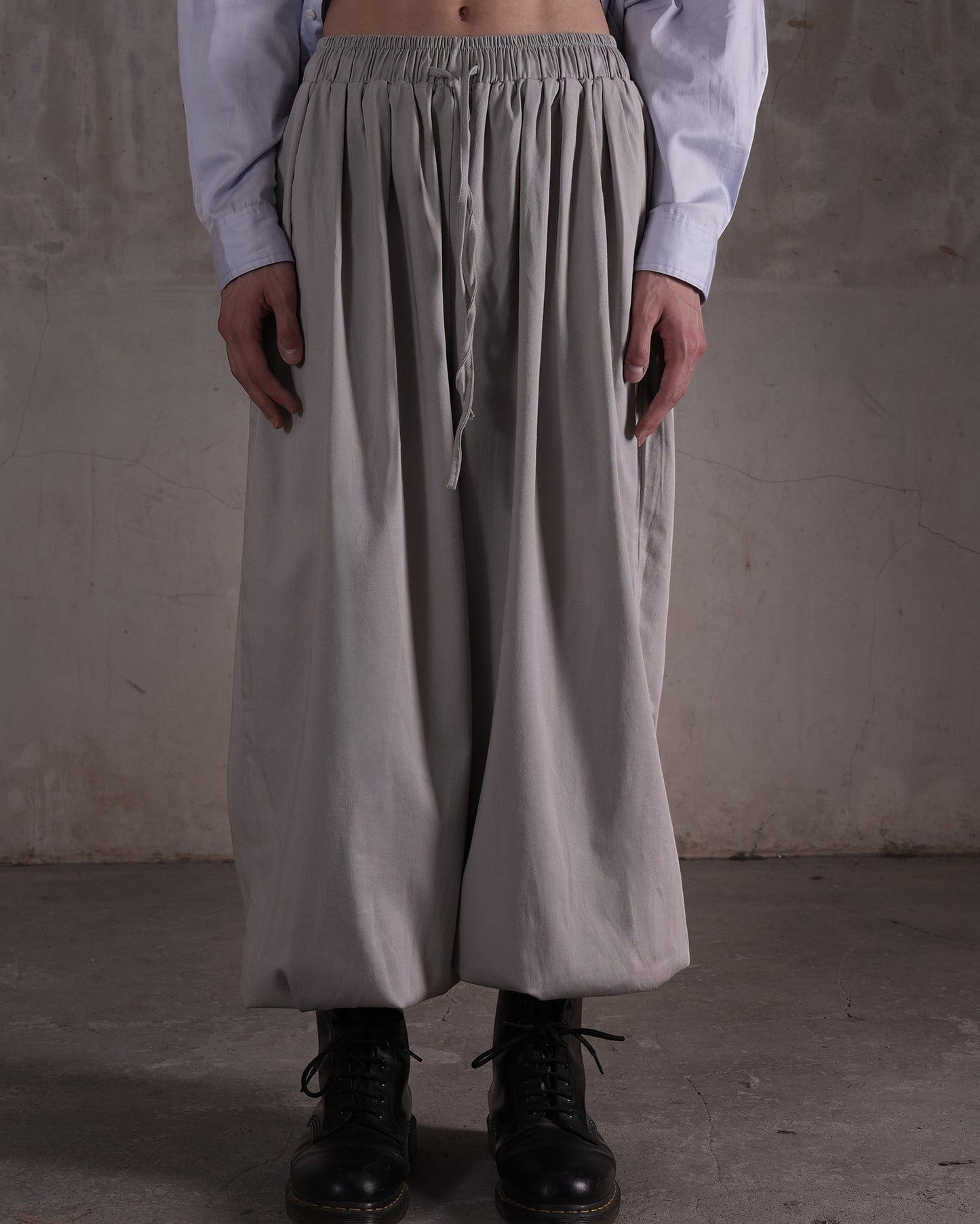 KYOHEY_FUJITAのグレーのマルチタックハーレムパンツ。ウエストゴムでドローストリング付きのゆったりとしたシルエット。