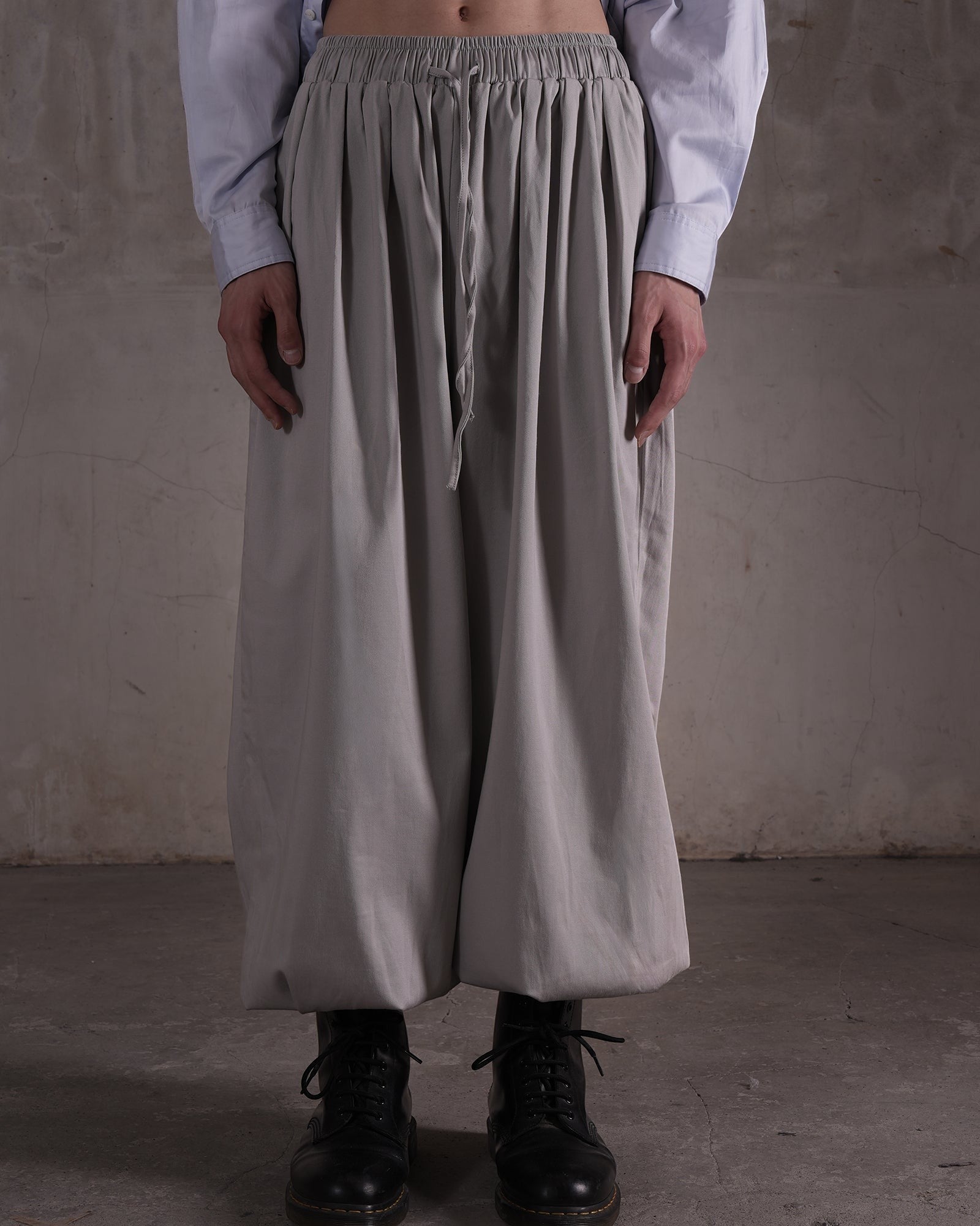 KYOHEY_FUJITAのグレーのマルチタックハーレムパンツ。ウエストゴムでドローストリング付きのゆったりとしたシルエット。