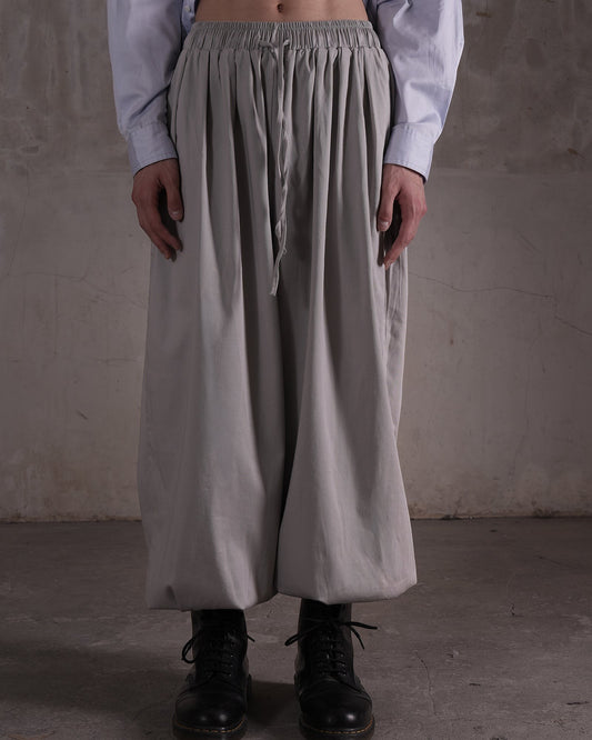 KYOHEY_FUJITAのグレーのマルチタックハーレムパンツ。ウエストゴムでドローストリング付きのゆったりとしたシルエット。