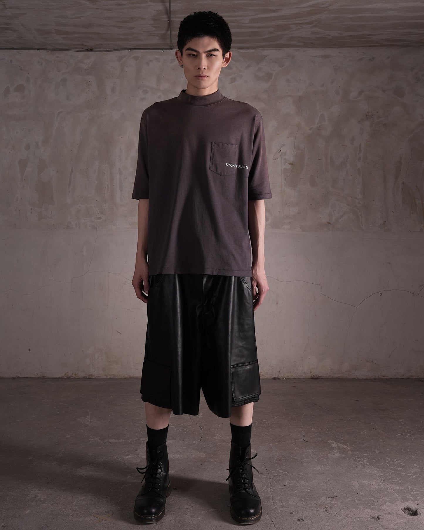 KYOHEY_FUJITAのヘビーウォッシュ加工されたモックネックロゴTシャツ。胸ポケットにロゴ入り、ダークグレーのコットン素材。