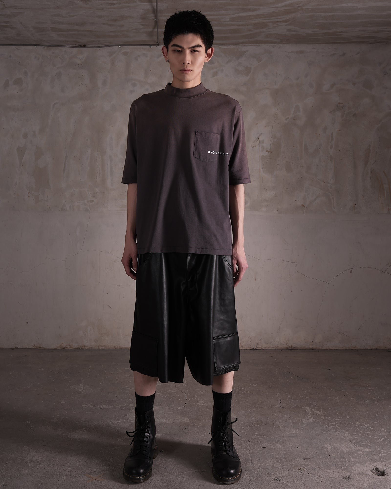 KYOHEY_FUJITAのヘビーウォッシュ加工されたモックネックロゴTシャツ。胸ポケットにロゴ入り、ダークグレーのコットン素材。