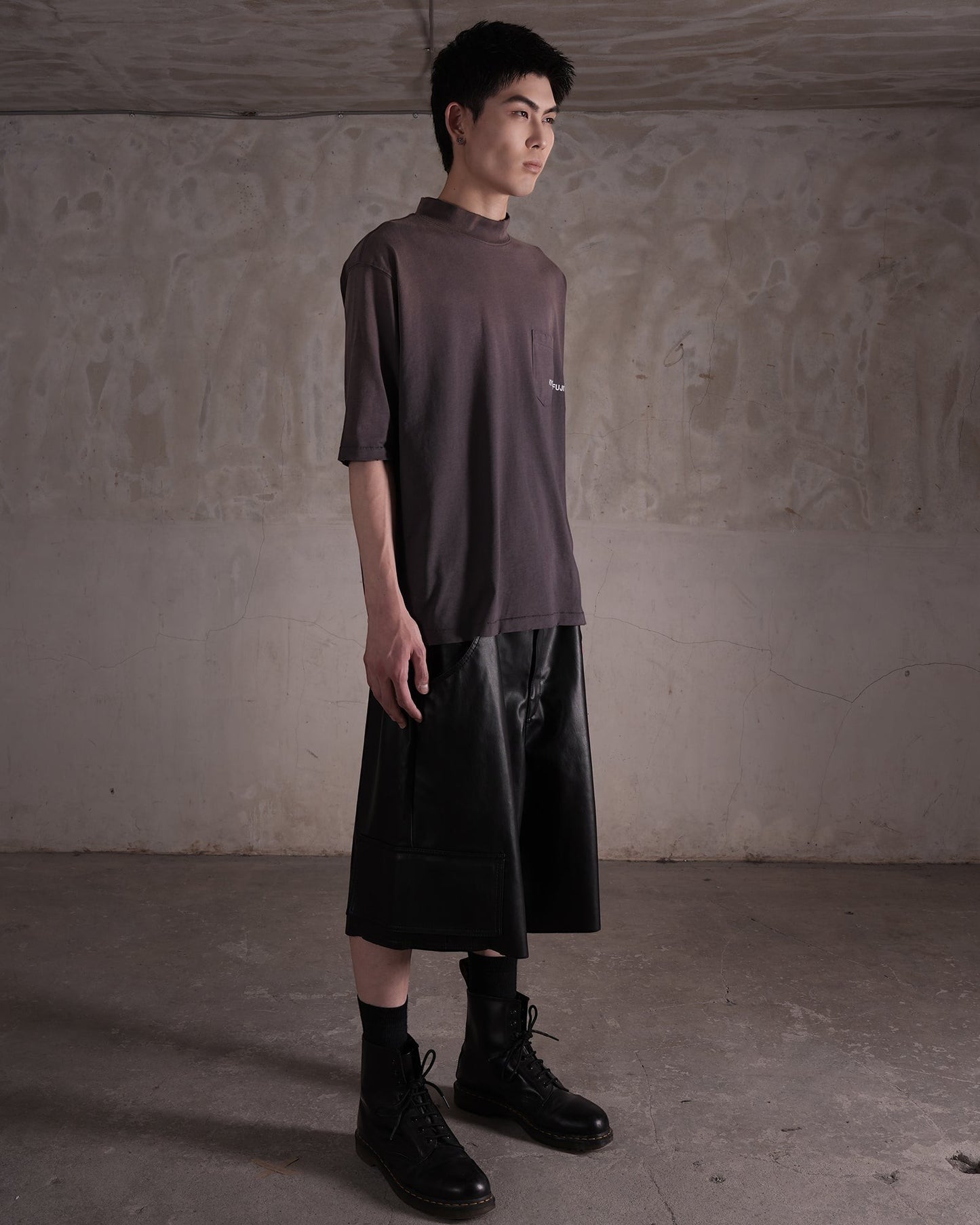 KYOHEY_FUJITAのヘビーウォッシュ加工モックネックロゴTシャツを着用した男性モデルのサイドビュー