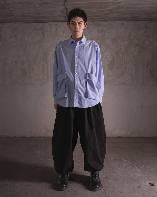 KYOHEY_FUJITAのオーバーサイズなストライプ柄シャツ。前面に大きなポケットが2つ付いたデコンストラクトデザインで、黒のワイドパンツと合わせています。