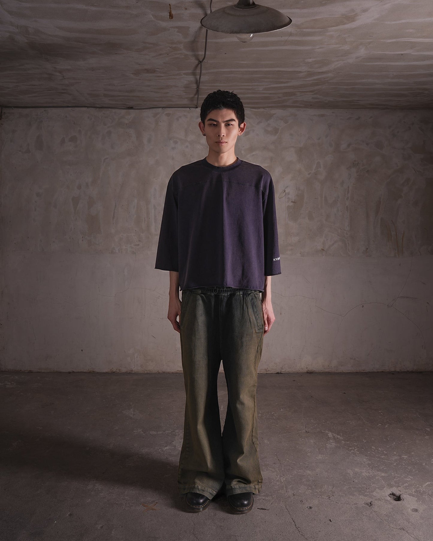 KYOHEY_FUJITAのヴィンテージ加工されたダークグレーのクロップド丈ボックスロゴTシャツを着用した男性モデル